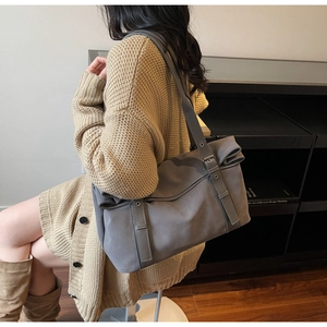 Détail d'un grand sac cabas gris foncé en daim avec sangles décoratives et boucles en métal