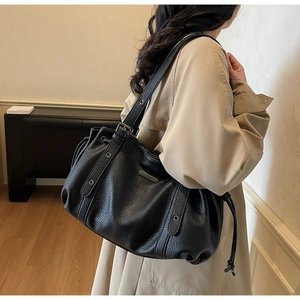 Close-up of black pleated tote bag with lychee texture leather and metal eyelet details