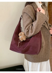 Detail of burgundy leather hobo bag with side stitching and plush bear charm