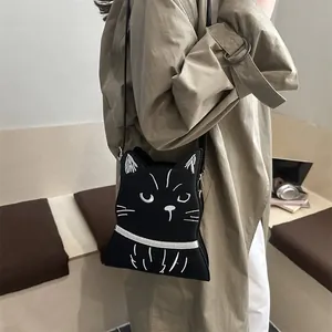 Détail du sac bandoulière chat noir mignon avec broderie faciale blanche et sangle noire