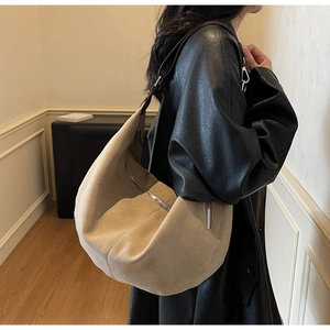 Vista dettagliata di una borsa hobo in pelle scamosciata beige sulla spalla