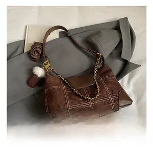 Detail of plaid suede underarm bag with vintage metal chain and plush glove charm