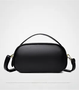Rear view of black pebble leather round handbag featuring gold hardware and curved handle