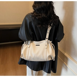 Detail of a creamy white tote bag with lychee grain leather texture and drawstring side