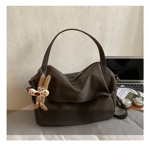 Detail of dark brown canvas tote bag with long shoulder strap and rabbit charm accessory