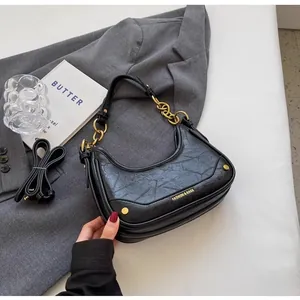 Detail of black crescent shoulder bag with pleated leather texture and gold chain strap
