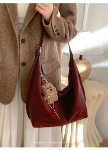 Detail of dark red leather tote bag with a cute plush puppy charm on the shoulder strap