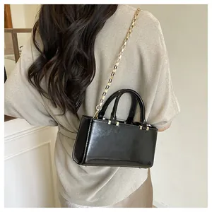 Detail shot of black leather handbag with gold chain strap and protective metal feet