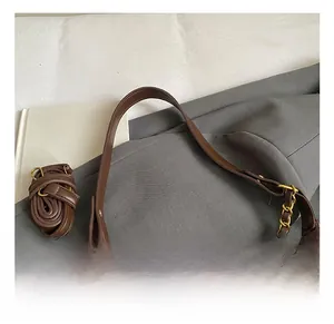 Detail of retro brown leather handbag with gold chain strap and fluffy white charm