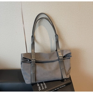 Gros plan du sac cabas gris mat avec boucles métalliques sur fond de livre design