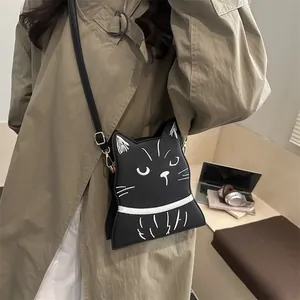 Gros plan du sac bandoulière chat en cuir noir avec détails de visage cousus en blanc