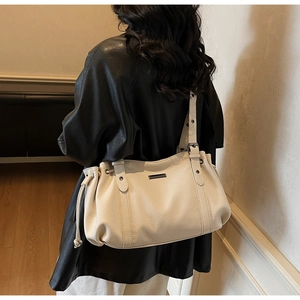 Detail of cream lychee-textured tote bag showing side drawstring and metal plate decoration