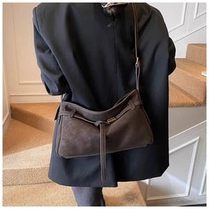 Close-up of chocolate brown tote bag with matte texture and gold buckle on a model
