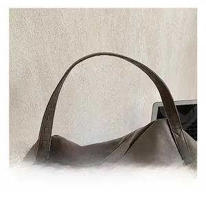 Close-up of the reinforced wide handle on this dark brown suede tote with fine stitching