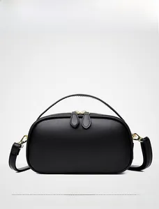 Detail of black pebbled leather handbag featuring gold-tone hardware and double zippers