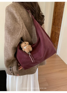 Detail of burgundy hobo bag with matte texture and a cute brown teddy bear charm