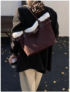 Close-up of a large dark brown suede tote bag with white faux fur trim and retro buckle