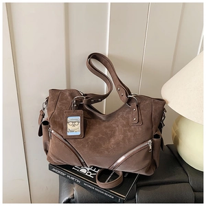 Detail of vintage brown tote bag with leather texture and bear charm on a desk