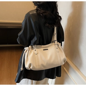 Detailed view of cream tote bag with adjustable eyelet strap and side drawstring details