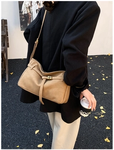 Detail view of khaki suede tote bag with slim strap and decorative buckle on autumn street