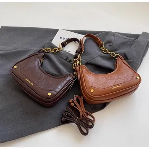 Flat lay of vintage crescent bags in dark brown and caramel with gold chain detail