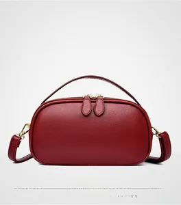 Detail of burgundy pebbled leather handbag featuring top handle and gold zipper hardware