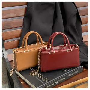 Detail of vintage tote bags in matte tan and glossy wine red with gold chain straps