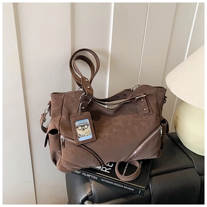 Detail of vintage brown tote bag showing metal zippers and crossbody strap design