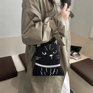 Détail du sac bandoulière chat noir créatif avec broderie blanche sur un trench kaki