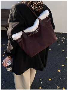 Détail du grand sac cabas en daim marron avec garniture en peluche blanche sur blazer noir