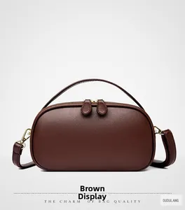 Detail view of brown pebbled leather texture and dual zipper hardware on semi-circle handbag