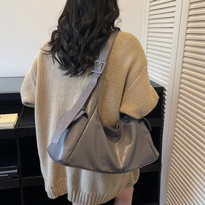 Minimalist dark grey large leather tote bag with pleats shown on model's shoulder
