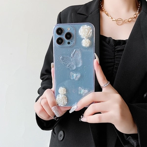 Coque iPhone bleu clair avec roses 3D et papillons pailletés tenue par un mannequin