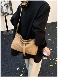 Detail of camel leather crossbody bag with gold buckle on a model in autumn street style