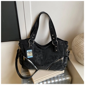 Detail of black faux leather tote bag with decorative bottom zipper and bear charm