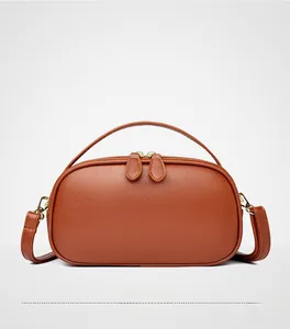 Detailed close-up of tan lychee grain leather handbag with gold zipper hardware