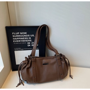 Close-up of brown litchi pattern tote bag with drawstring texture and metal eyelet straps
