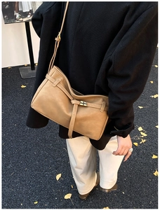 Detailed view of caramel leather tote bag featuring golden cross-hatch metal buckle