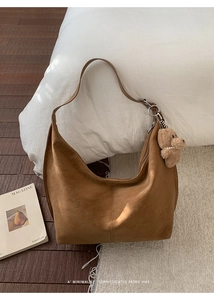 Detailed view of caramel suede hobo bag with zipper closure and plush bear pendant detail