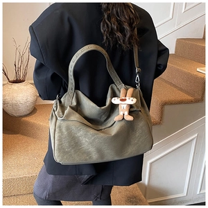 Detail view of large olive green tote bag with decorative rabbit pendant on a model
