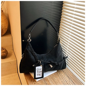 Detail of black leather hobo bag with braided shoulder strap and vintage pendant
