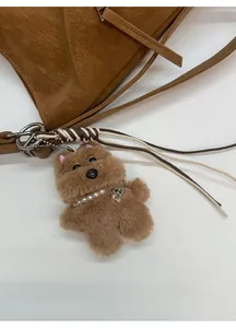 Close-up of brown plush dog charm with pearl necklace on a lychee leather tote bag