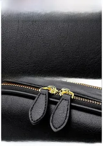 Close-up of black pebble grain leather handbag with gold dual-zipper detail