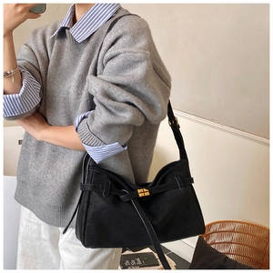Detail of matte black tote bag with gold buckle and leather strap on casual outfit
