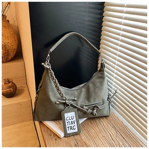 Close-up of green leather hobo bag with woven strap and decorative coin pouch charm