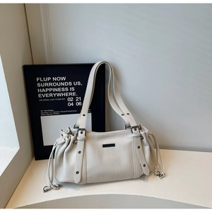 Detail of creamy white pebble leather tote bag with drawstring side and matte black hardware