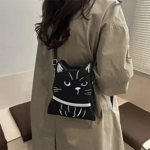 Détail du sac à bandoulière chat noir avec broderie blanche des traits du visage