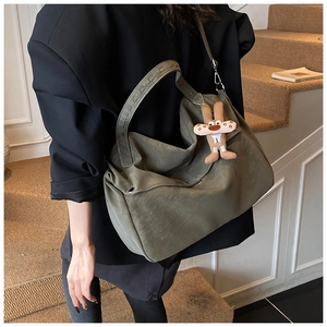 Detail of olive green frosted tote bag with plush charm and adjustable strap