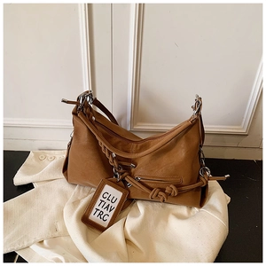 Detail view of large brown hobo bag featuring woven strap and decorative leather tag