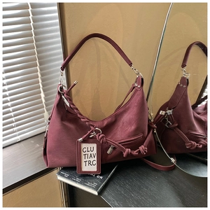 Detail of burgundy leather hobo bag featuring woven knot accents and a decorative tag